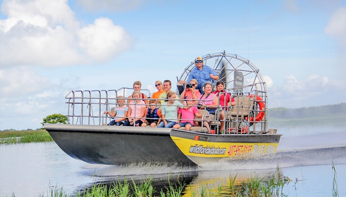 Guests on an airboat tour in the Everglades, gliding through wetlands.