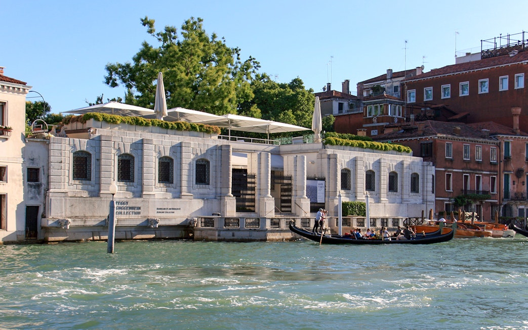 Peggy Guggenheim Collection museum along Venice's Grand Canal with gondola passing by.