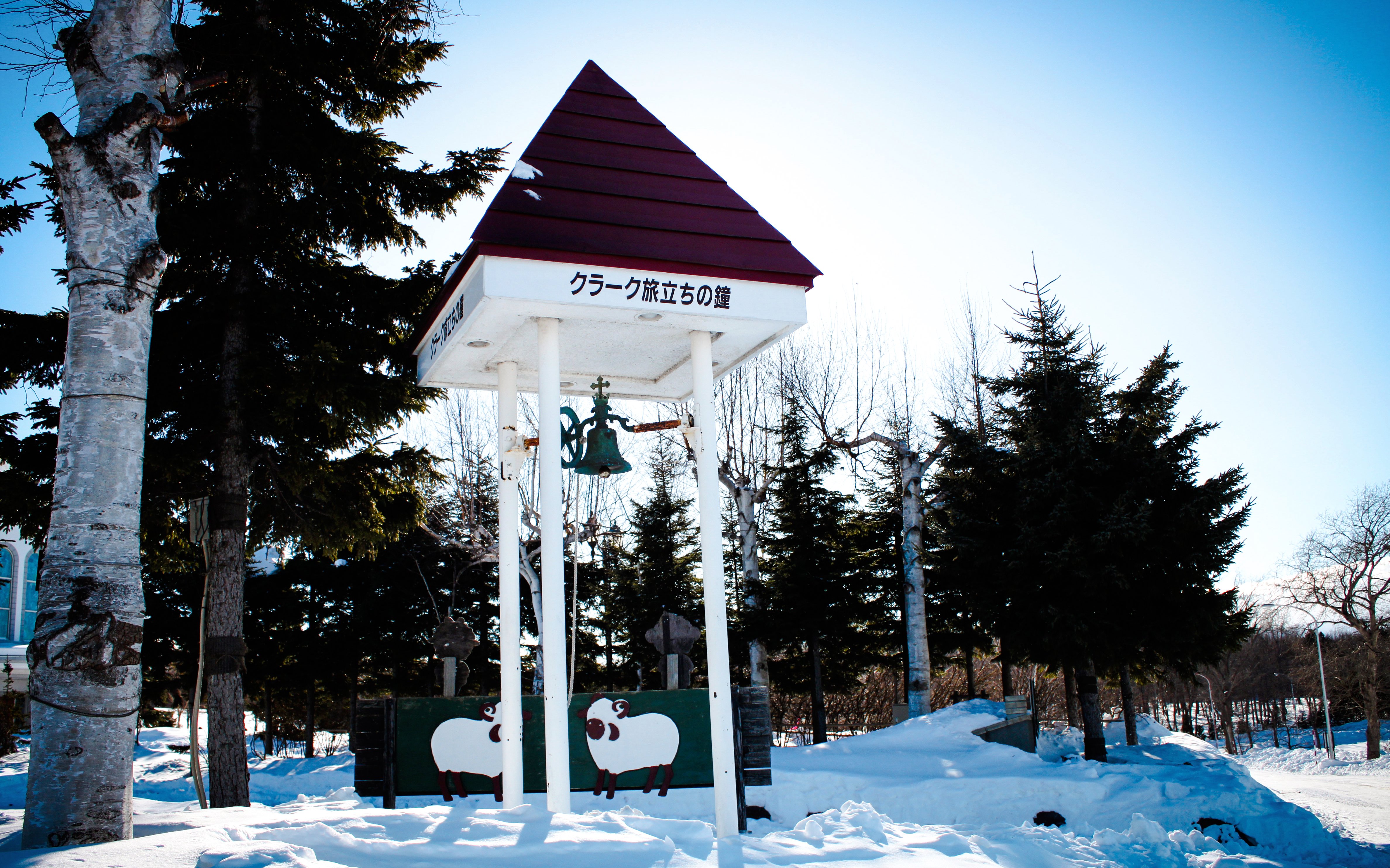 Clark's Departure Bell monument at Asahiyama Zoo, Hokkaido, Japan, surrounded by snow and trees.