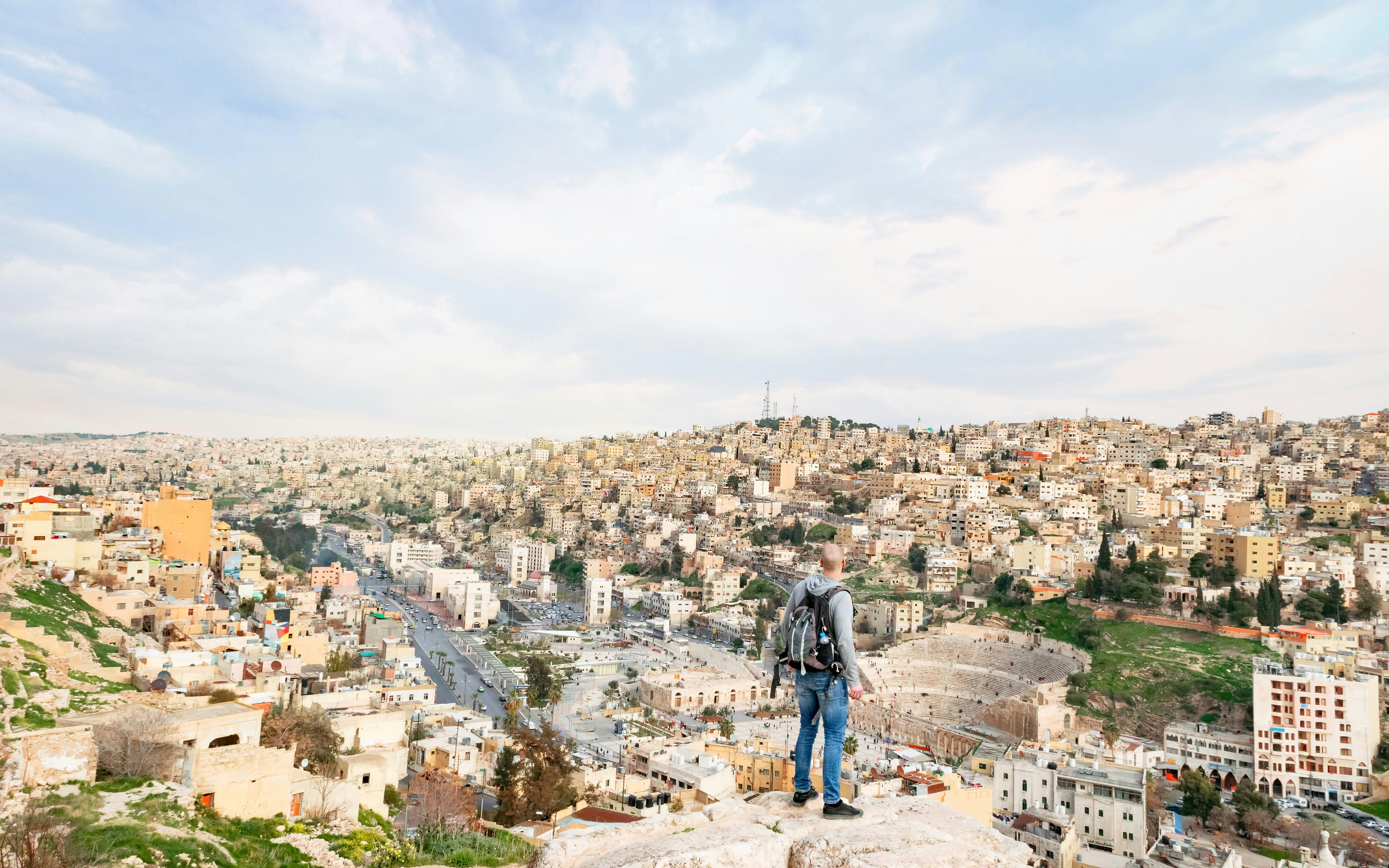 Visitor overlooking Roman Amphitheater and cityscape in Amman, Jordan.