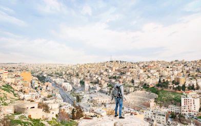 Visitor overlooking Roman Amphitheater and cityscape in Amman, Jordan.