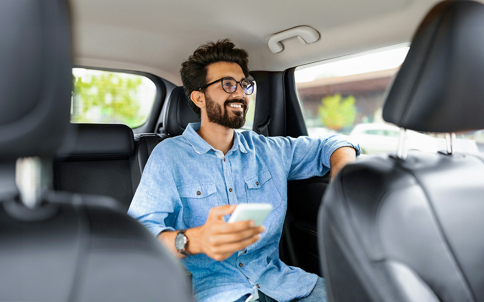 Man enjoying private car transfer during tour, holding phone.