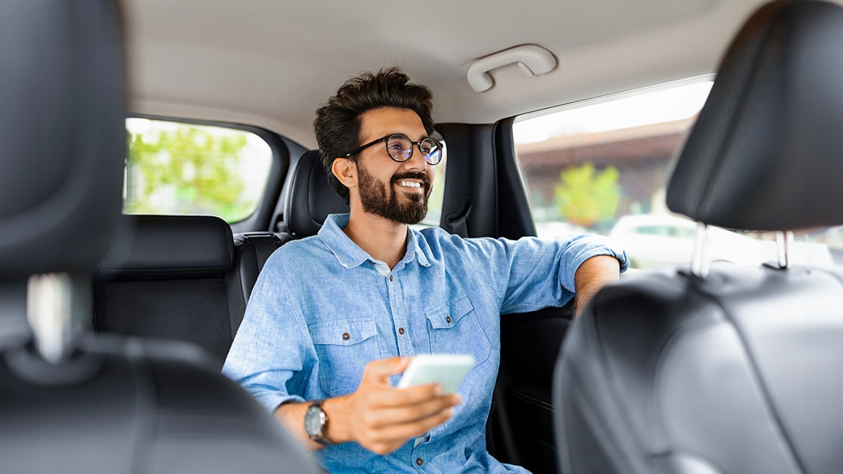Man enjoying private car transfer during tour, holding phone.