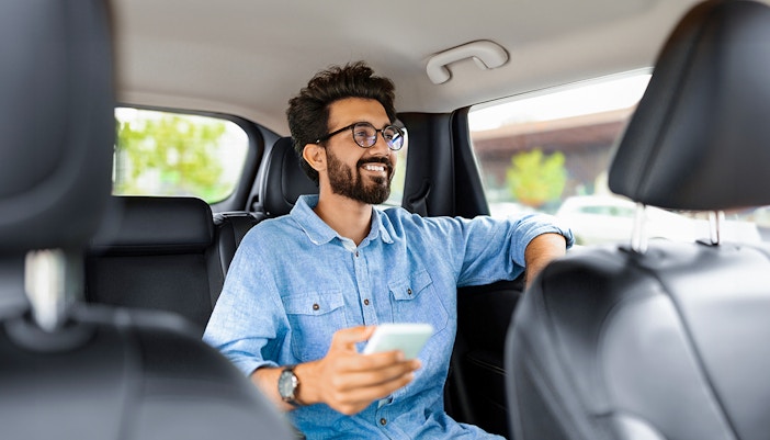 Man enjoying private car transfer during tour, holding phone.