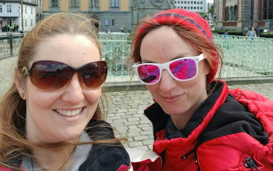 Two people smiling in front of a historic building in Bergen during a self-guided city exploration game.