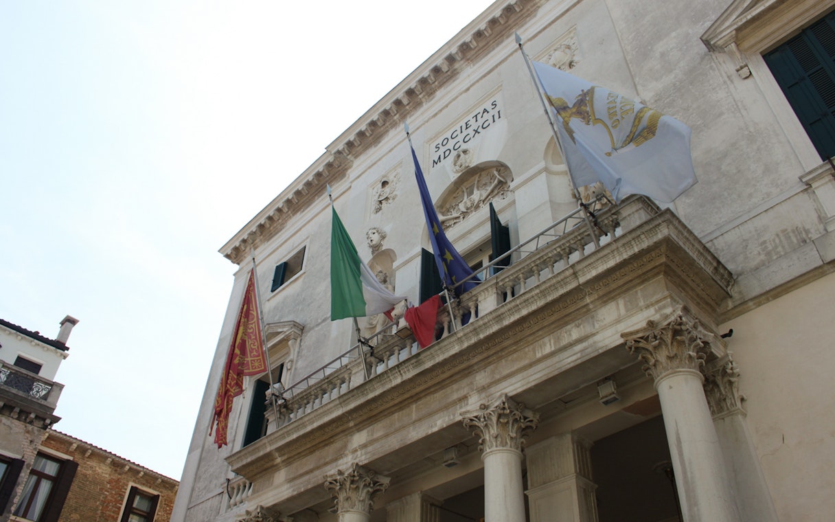 Facade of a historic building with flags in Venice, Italy.