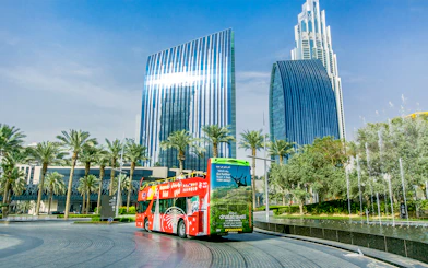 Open-top tour bus near modern skyscrapers in Dubai on Hop-On Hop-Off Tour with Al Seef Dhow Cruise.