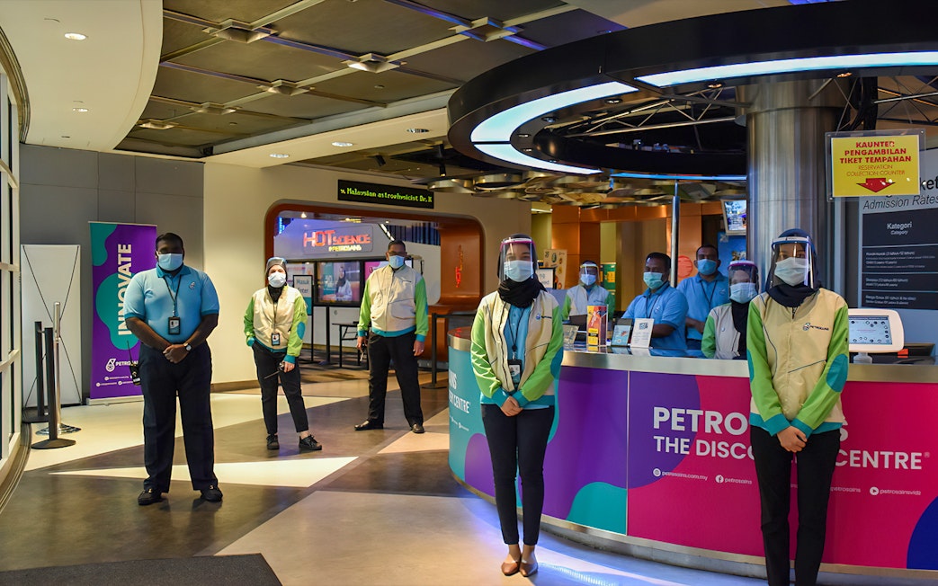 Staff at Petrosains, The Discovery Centre entrance in Kuala Lumpur, Malaysia, wearing masks and face shields.