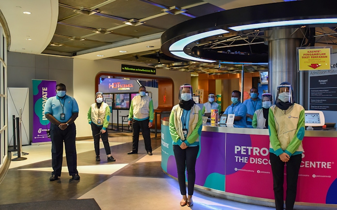 Staff at Petrosains, The Discovery Centre entrance in Kuala Lumpur, Malaysia, wearing masks and face shields.