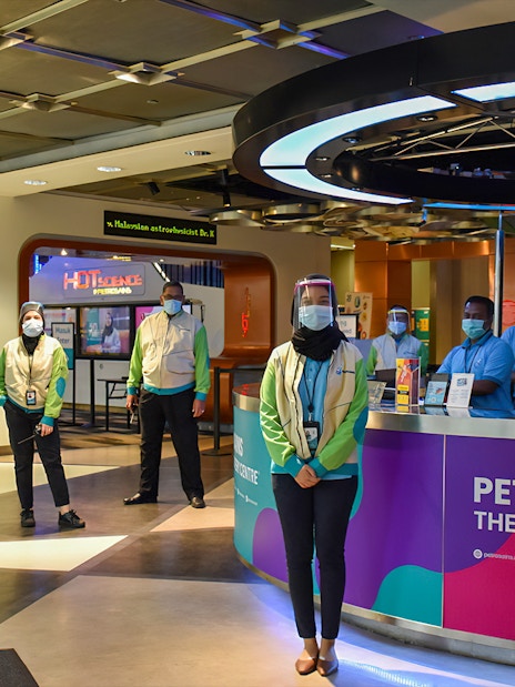 Staff at Petrosains, The Discovery Centre entrance in Kuala Lumpur, Malaysia, wearing masks and face shields.