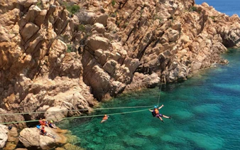 Coasteering adventure along rocky cliffs in Costa Smeralda, Porto Cervo, with participants in safety gear.
