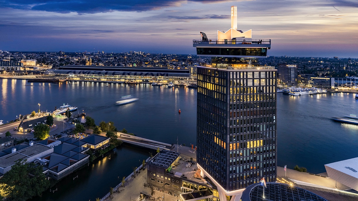 A'DAM Lookout tower overlooking Amsterdam cityscape and river at dusk.