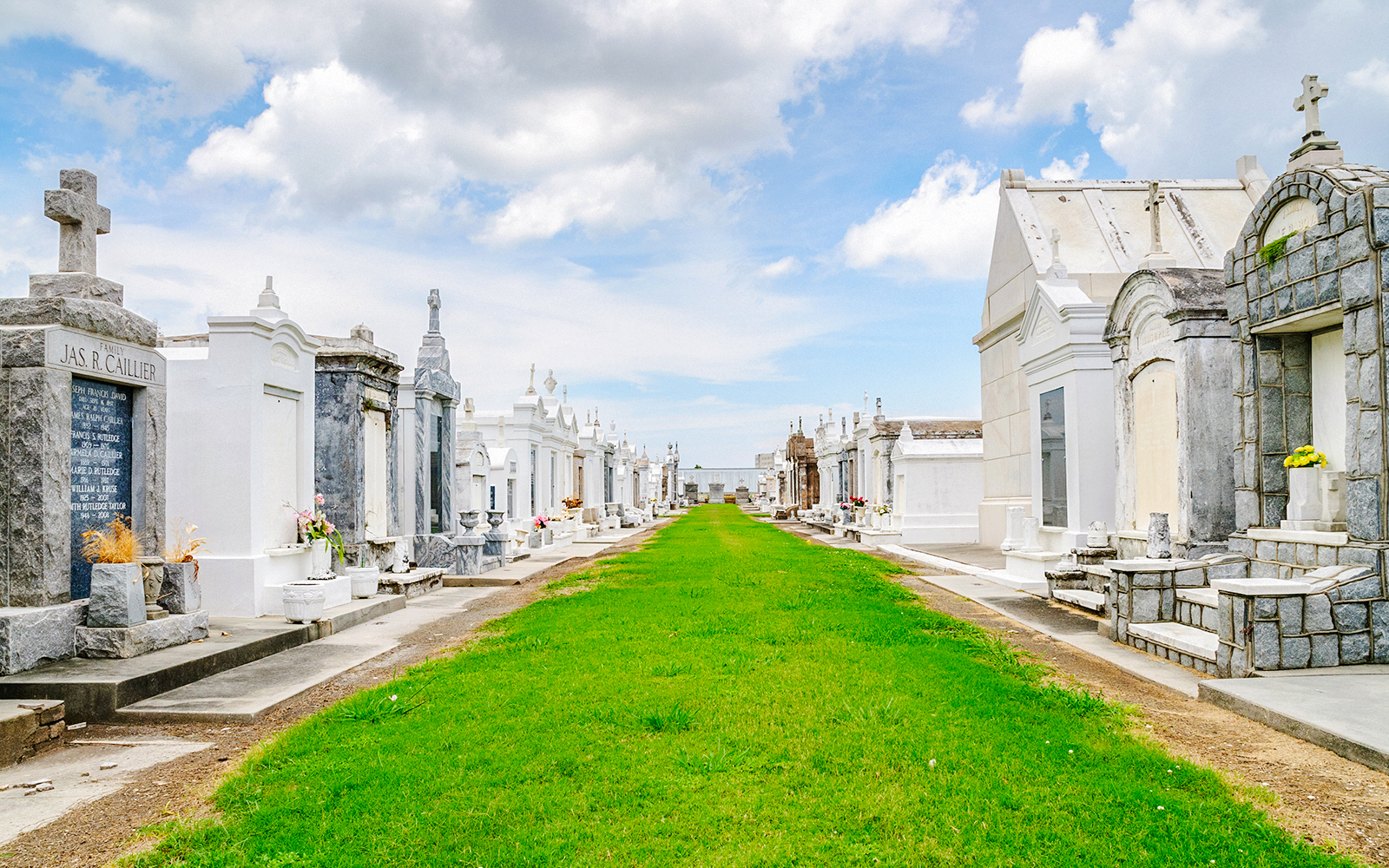 Saint Louis Cemetery #3 with above-ground tombs and a grassy pathway in New Orleans.