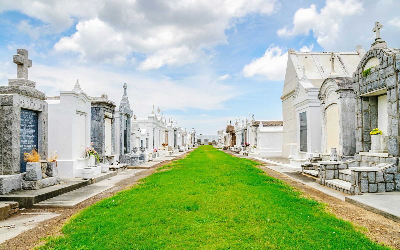 Saint Louis Cemetery #3 with above-ground tombs and a grassy pathway in New Orleans.