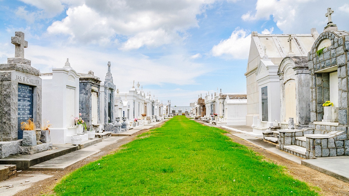 Saint Louis Cemetery #3 with above-ground tombs and a grassy pathway in New Orleans.