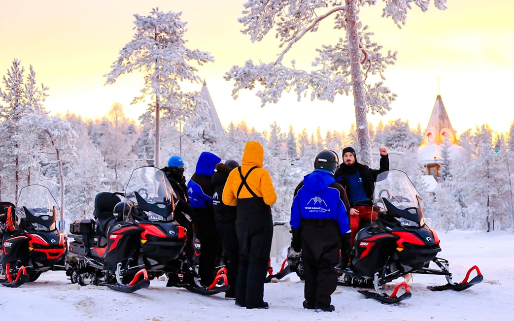 Guests preparing for snowmobiling adventure in snowy Rovaniemi forest.