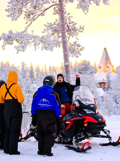 Guests preparing for snowmobiling adventure in snowy Rovaniemi forest.