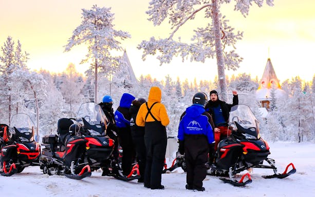Guests preparing for snowmobiling adventure in snowy Rovaniemi forest.