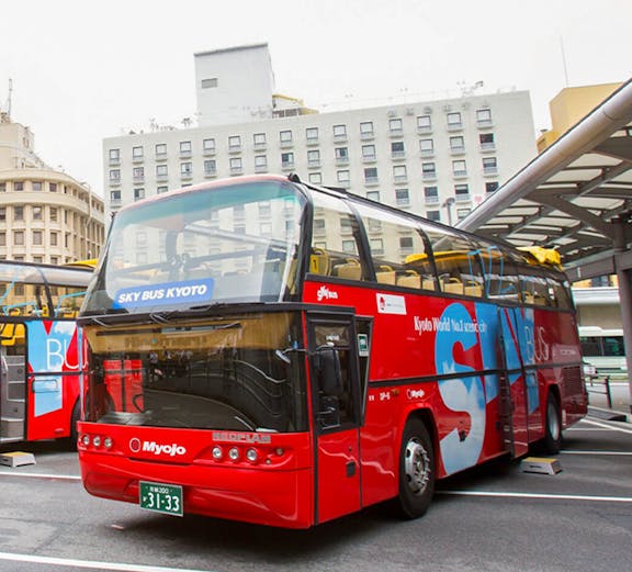 Red double-decker bus for Kyoto city tour parked at a station.