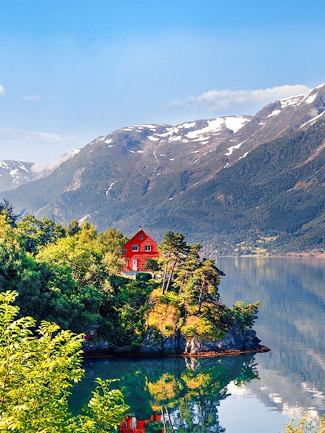 Small village house by Hardangerfjorden with surrounding mountains and lush greenery.