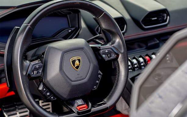 Black Lamborghini Aventador steering wheel with control buttons.
