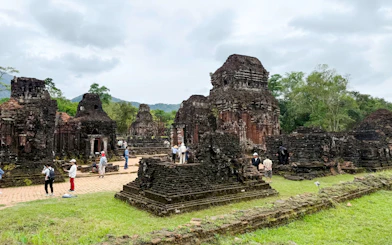Ancient temple ruins at My Son Sanctuary, Quang Nam, Vietnam, with tourists exploring the site.