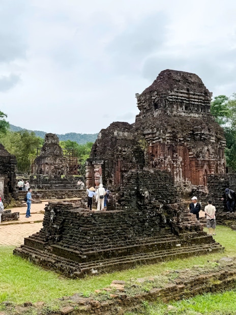 Ancient temple ruins at My Son Sanctuary, Quang Nam, Vietnam, with tourists exploring the site.