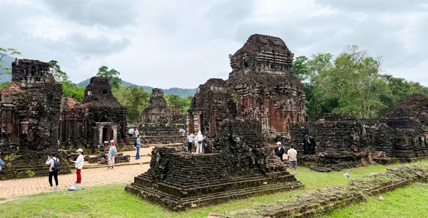 Ancient temple ruins at My Son Sanctuary, Quang Nam, Vietnam, with tourists exploring the site.