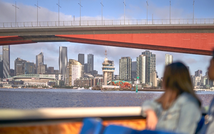 Melbourne skyline viewed from a river cruise under a bridge.