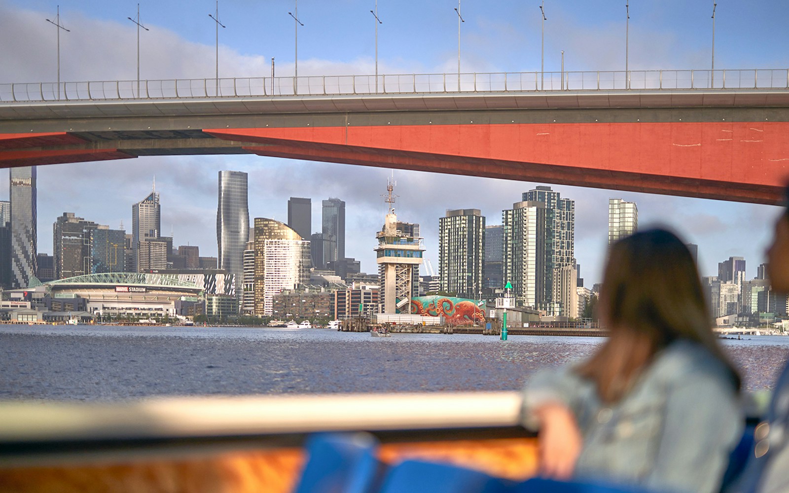Melbourne skyline viewed from a river cruise under a bridge.