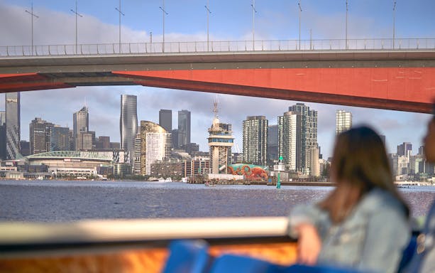 Melbourne skyline viewed from a river cruise under a bridge.