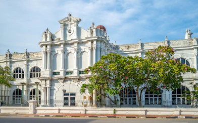 Historic facade of Penang State Museum and Art Gallery, Malaysia, with arched windows and lush greenery.