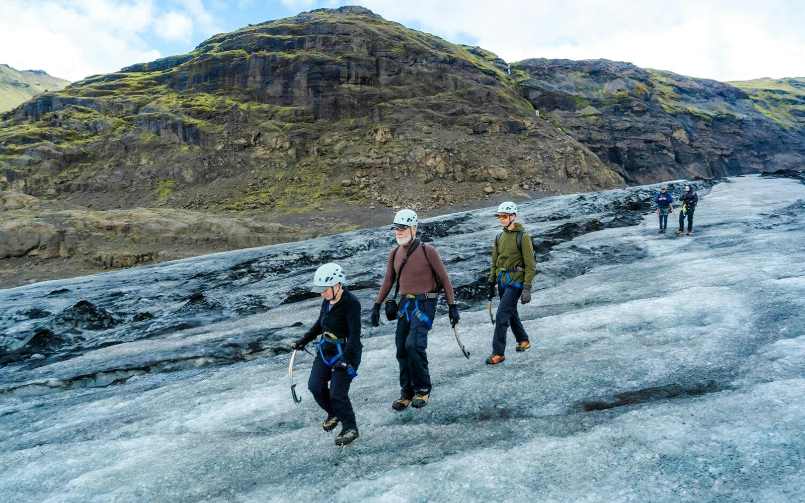 Hikers exploring Sólheimajökull glacier in Iceland with ice axes and helmets.