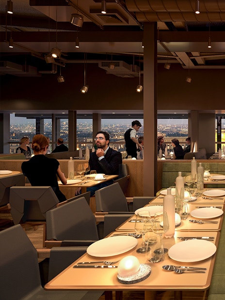 Dining area inside Eiffel Tower's Madame Brasserie with city view.
