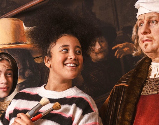 Visitors interacting with Rembrandt wax figure at Madame Tussauds Amsterdam.