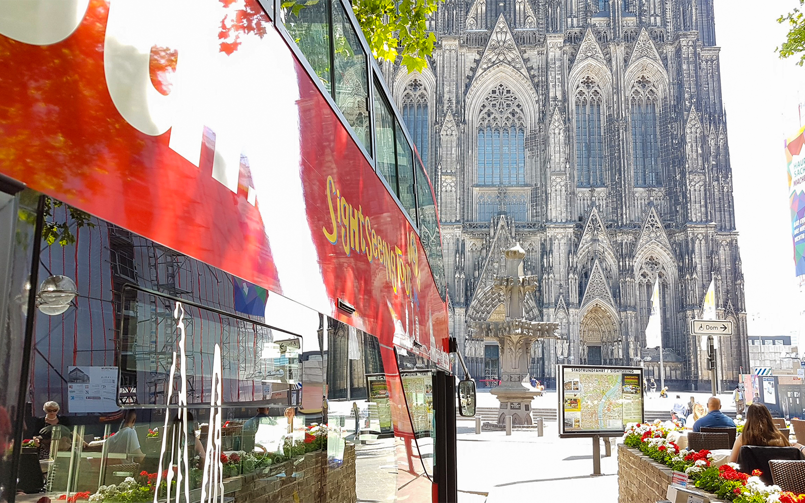 Hop on hop off bus near Cologne Cathedral with Gothic architecture in background.