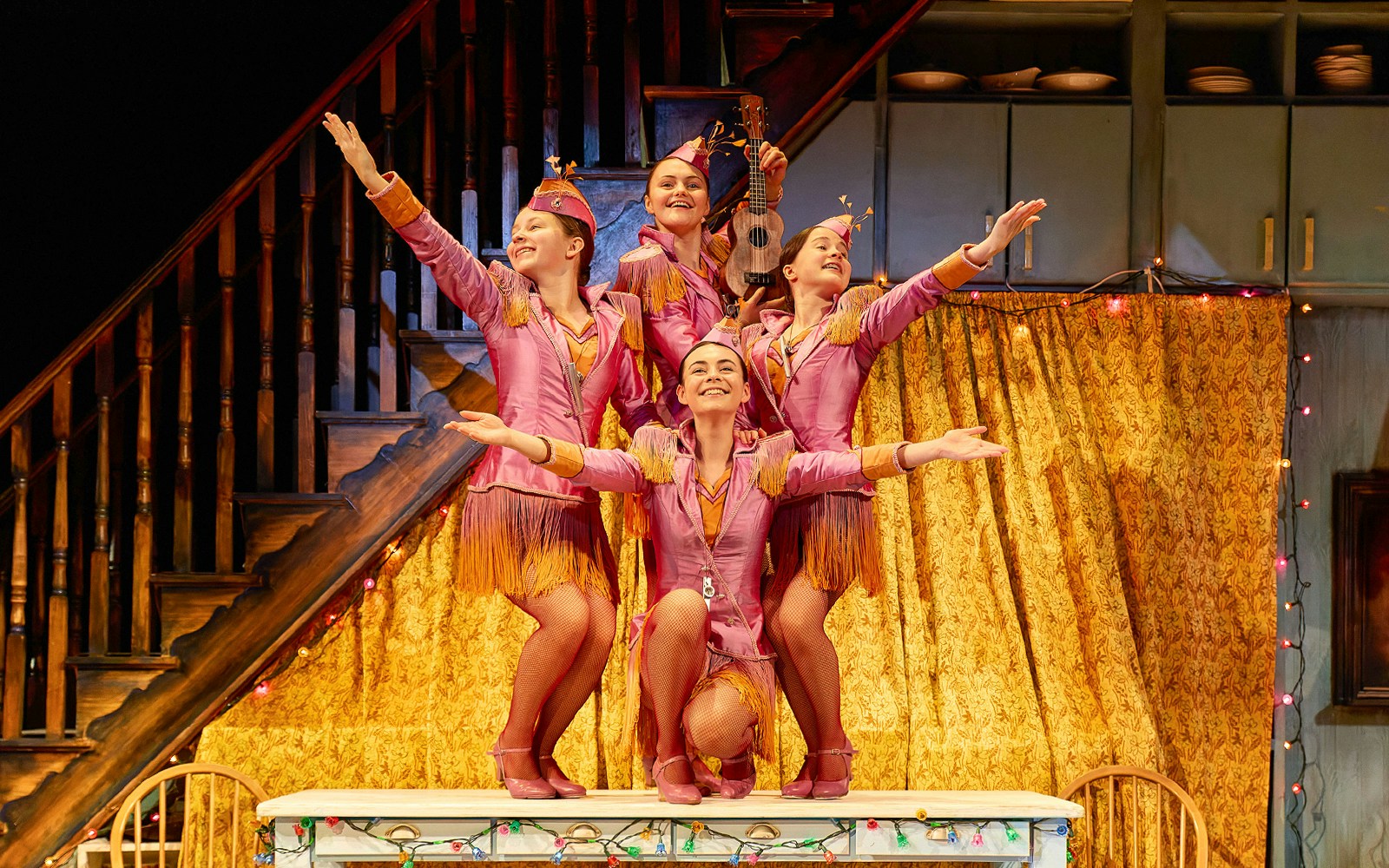 Performers in pink costumes on stage in a California theater show.