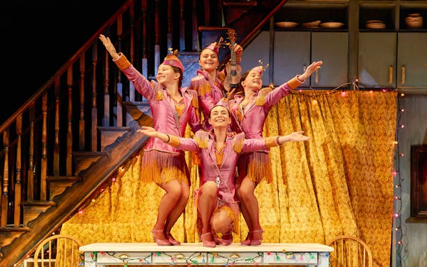 Performers in pink costumes on stage in a California theater show.