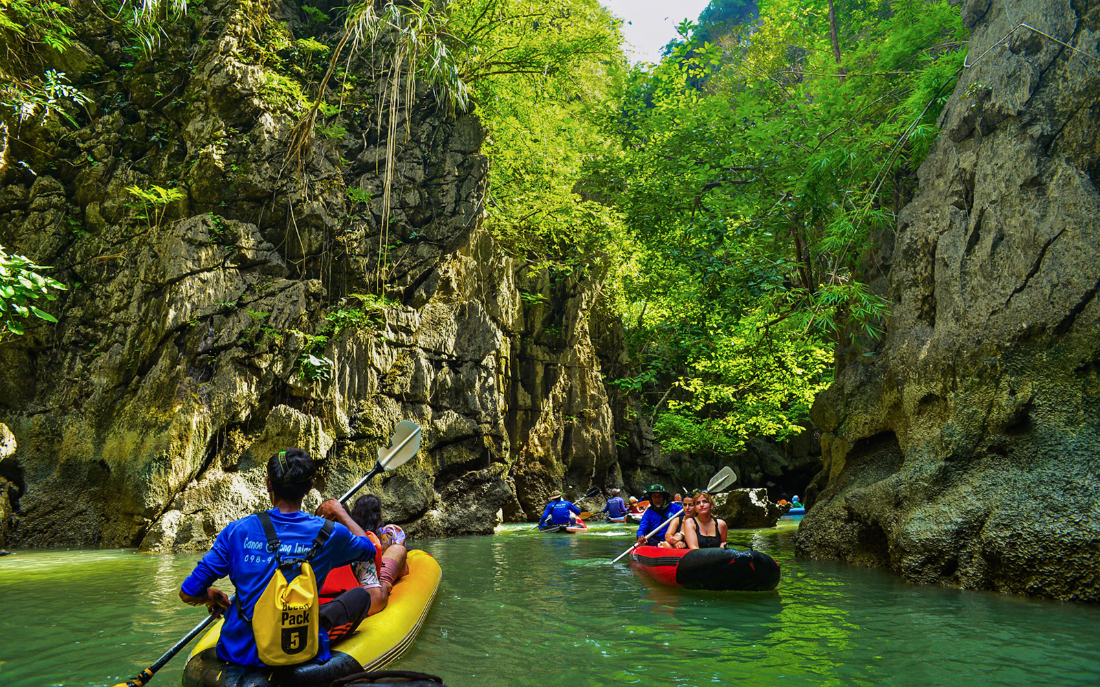 Tourists kayaking through limestone cliffs at Phang Nga Bay, Thailand.