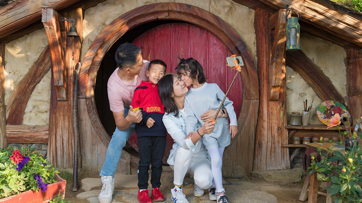 Family taking selfie at Hobbiton Movie Set entrance, Auckland tour.