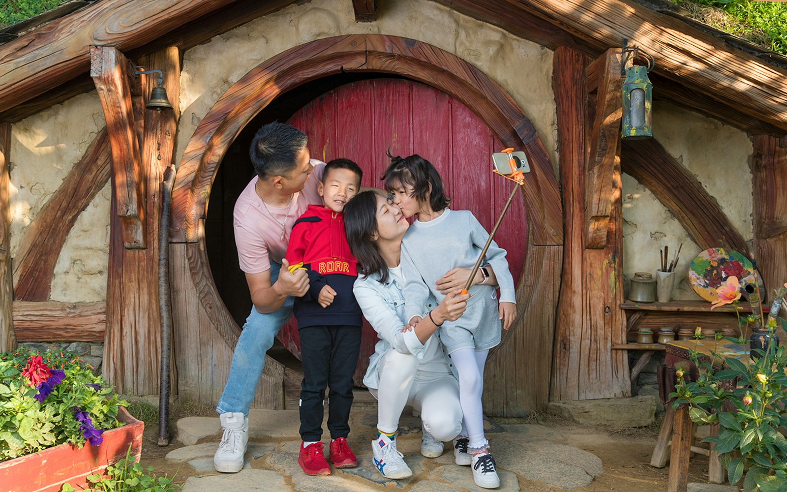 Family taking selfie at Hobbiton Movie Set entrance, Auckland tour.