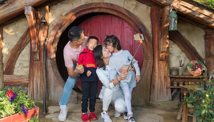Family taking selfie at Hobbiton Movie Set entrance, Auckland tour.