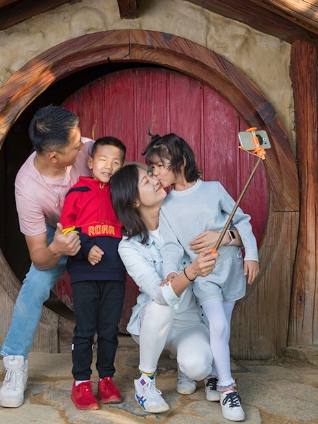 Family taking selfie at Hobbiton Movie Set entrance, Auckland tour.