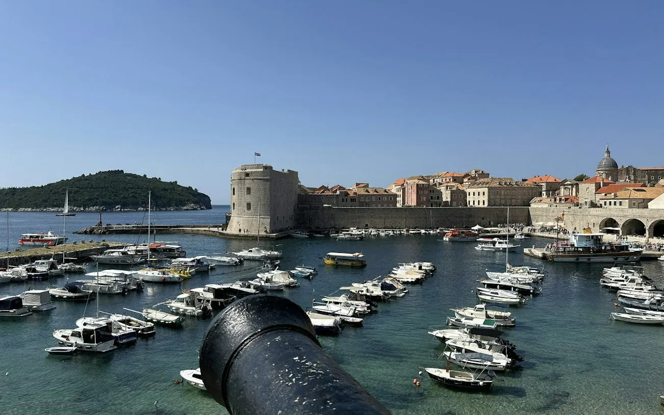 Dubrovnik harbor with medieval city walls and boats, view from a cannon.