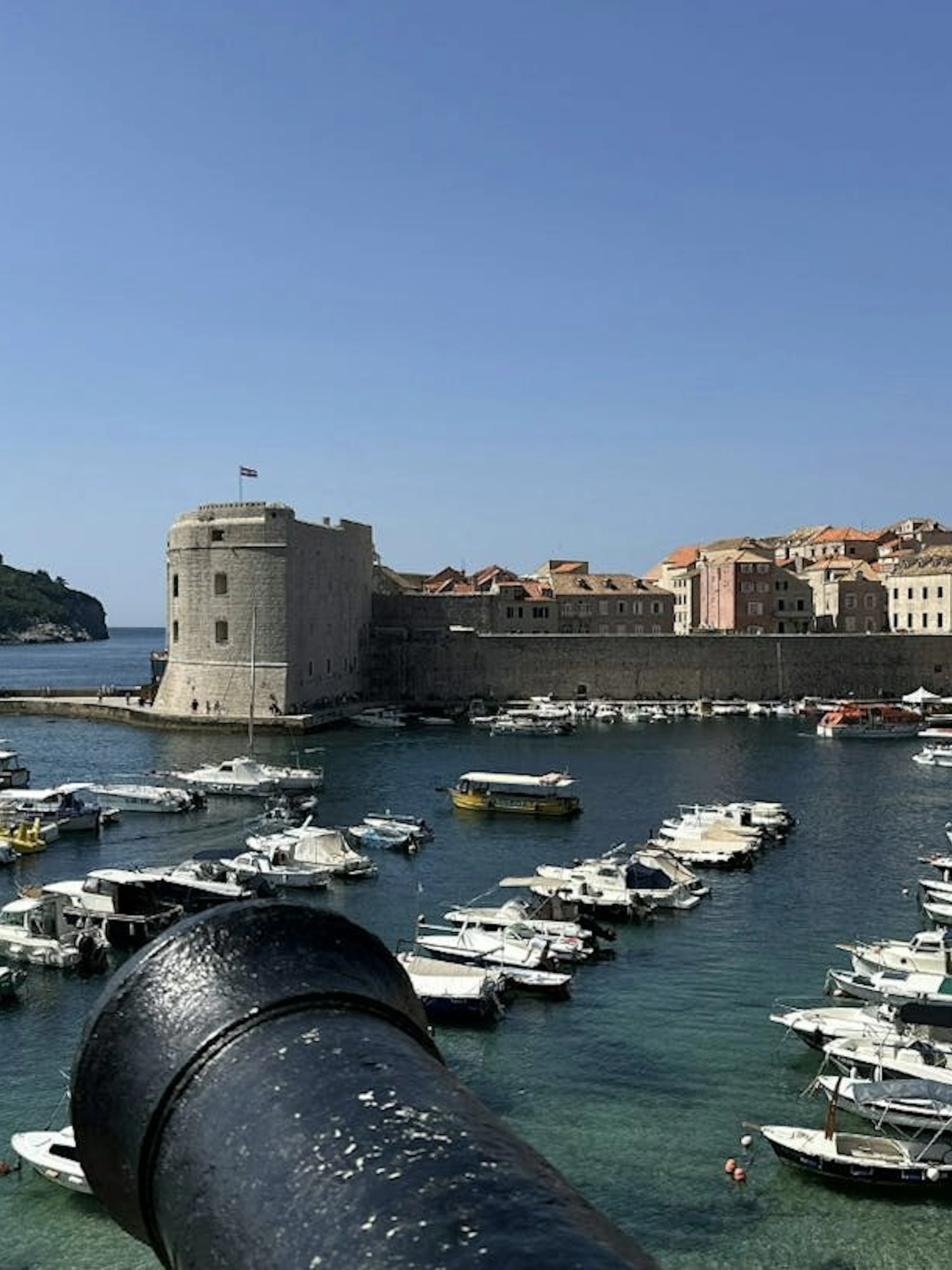 Dubrovnik harbor with medieval city walls and boats, view from a cannon.