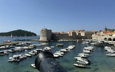 Dubrovnik harbor with medieval city walls and boats, view from a cannon.