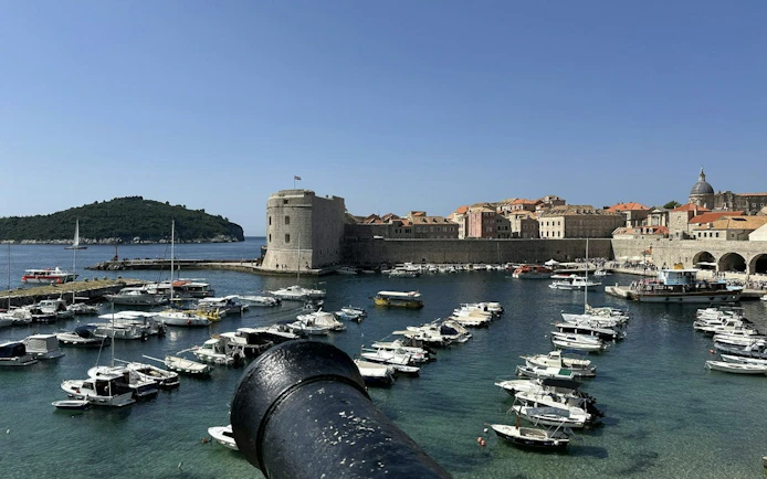 Dubrovnik harbor with medieval city walls and boats, view from a cannon.