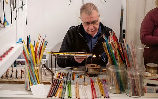 Glass artisan crafting with colorful rods in Venice workshop.