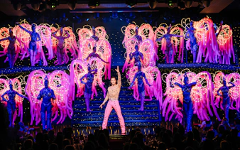 Performers on stage at the Moulin Rouge Show in Paris with vibrant costumes and lights.