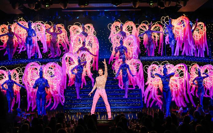 Performers on stage at the Moulin Rouge Show in Paris with vibrant costumes and lights.